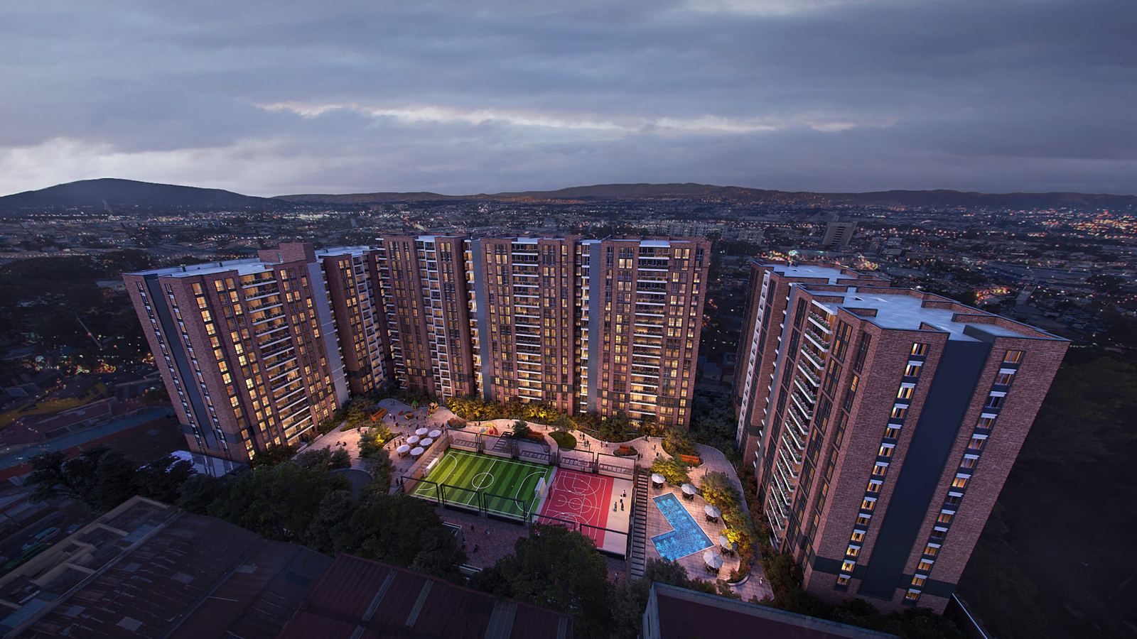 Vista aérea del conjunto residencial Parque Mateo: torres, canchas deportivas y área de amenidades al atardecer