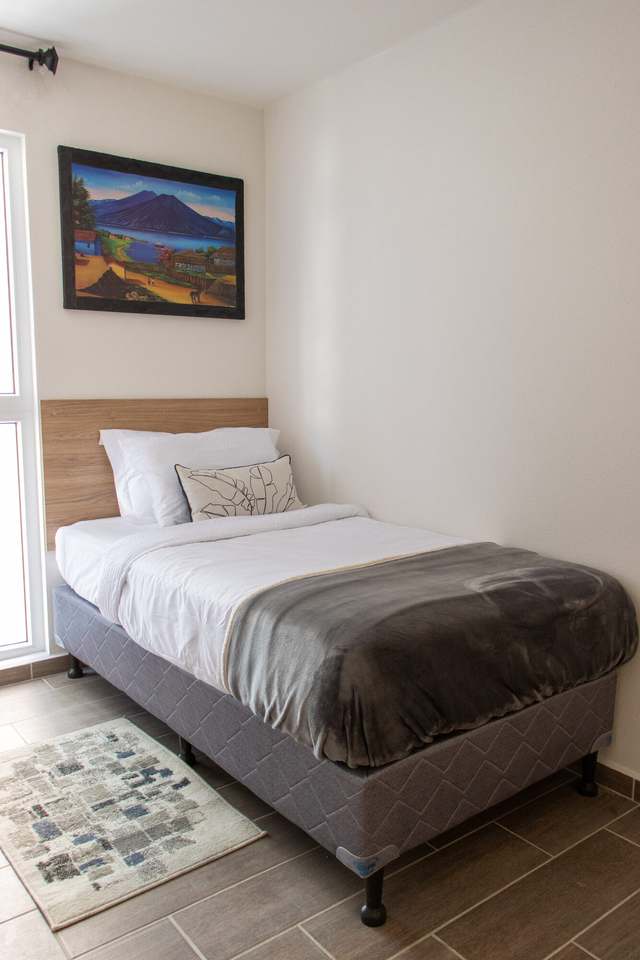 Segundo dormitorio con cama individual y cuadro de Atitlán