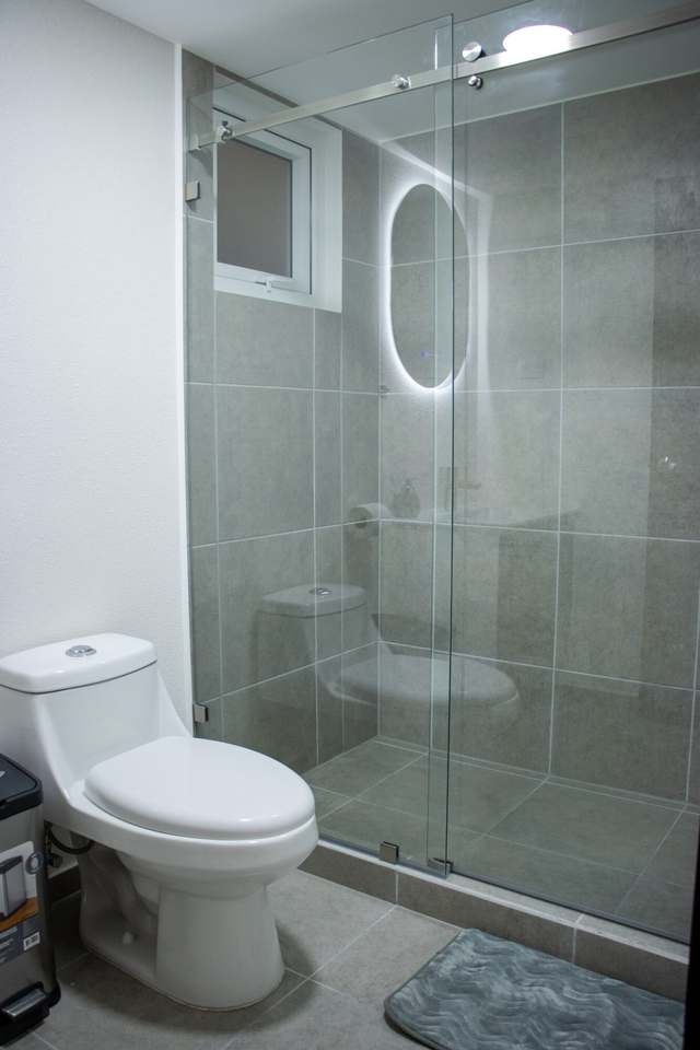 Baño con inodoro y ducha de vidrio